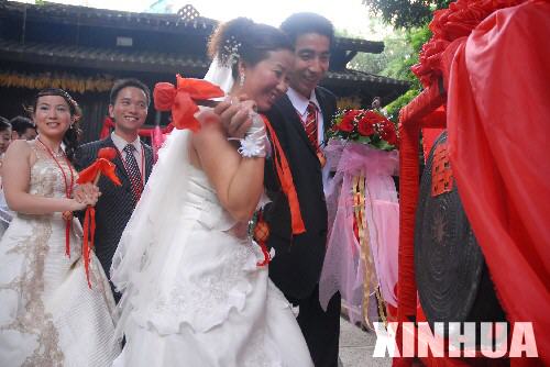 9月30日,新人们在水族村寨敲“同心鼓”。 当日,第八届“龙凤大典”集体婚礼在深圳锦绣中华·民俗村举行。109对新人喜结良缘,并体验了丰富多彩的少数民族婚俗。 新华社发(袁水灵 摄)